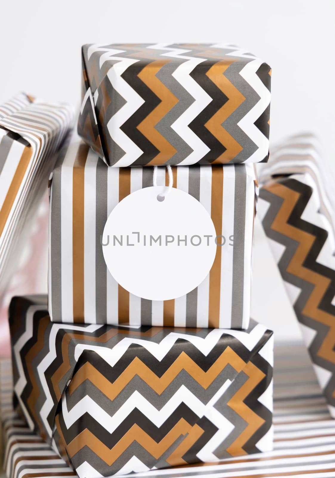 Present with blank gift tag close up. Gift boxes wrapped in Striped and chevron geometric paper. Christmas, New Year, Birthday, Anniversary label mockup