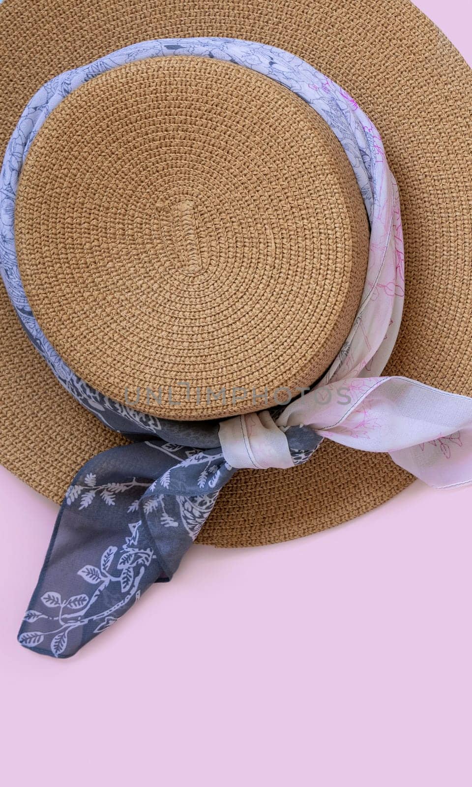 Female straw hat with fabric decor top view on light pink with copy space. Summer Travel concept