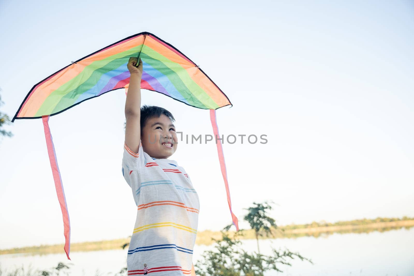 Asian happy children boy with a kite running to fly on in park at summer sunset outdoors