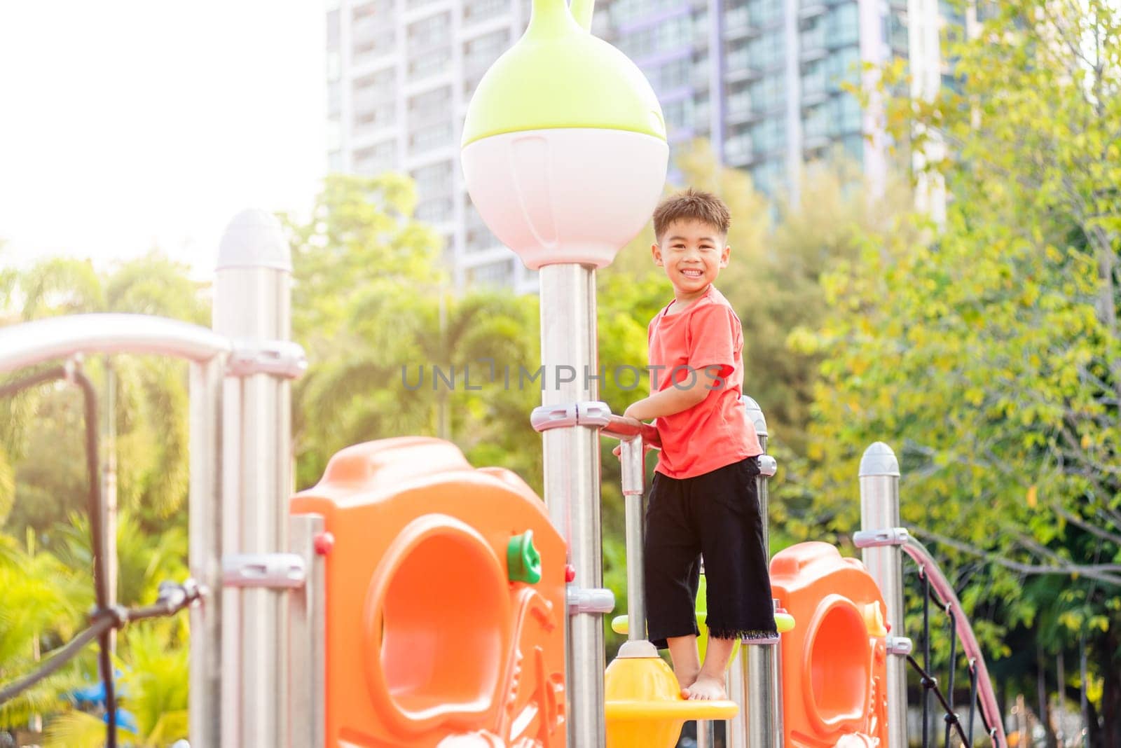 Asian child playing on outdoor playground, happy preschool little kid having funny while playing on the playground equipment in the daytime in summer, Outside education, Little boy climbing