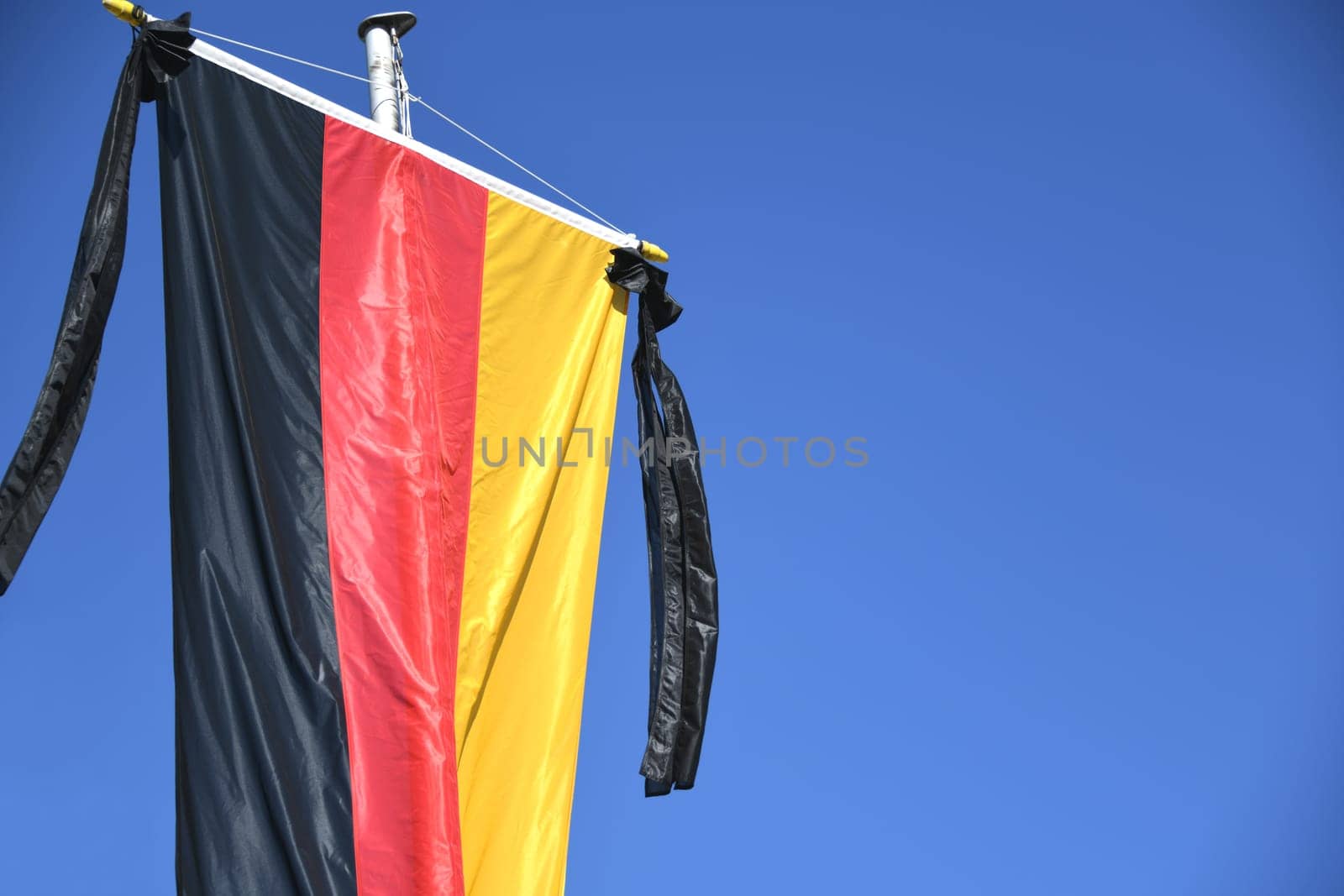 The national flag of the Federal Republic of Germany,black,red and gold,hangs on the flagpole. As a symbol of national mourning,the mourning ribbon is attached to the flag with two black ribbons.