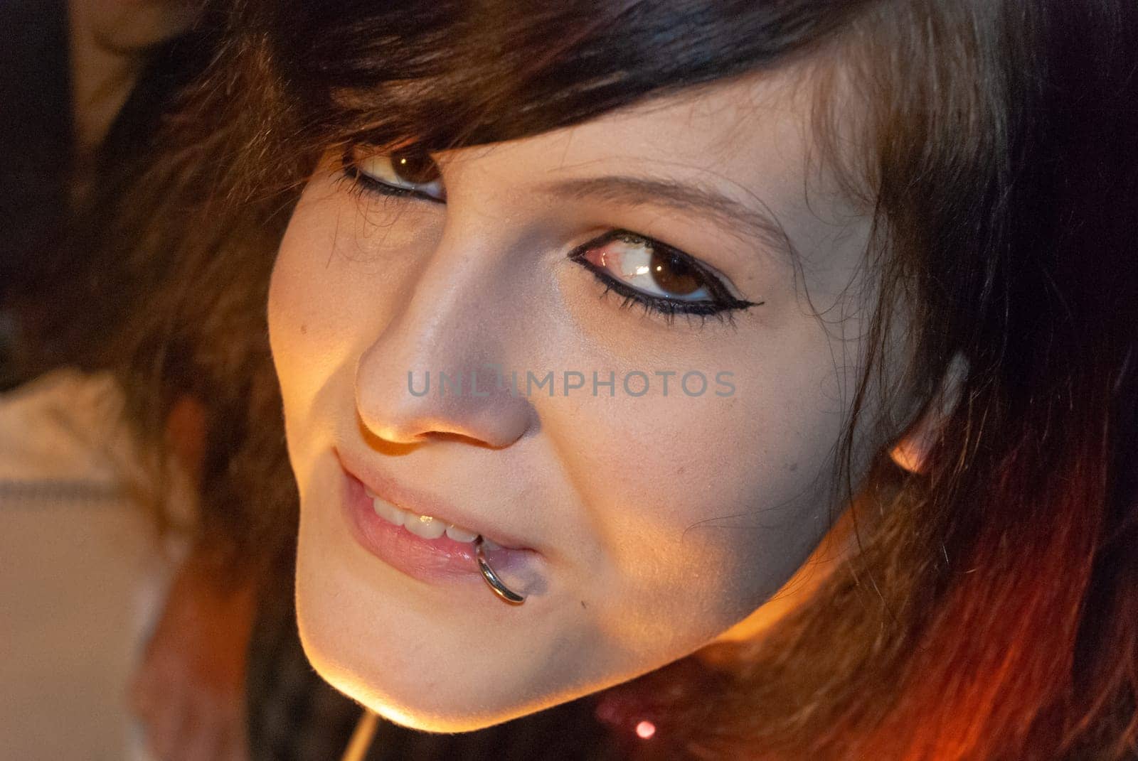 Young punk emo Girl with piercing, with red and black hair, smiling at camera, view from high angle, close-up