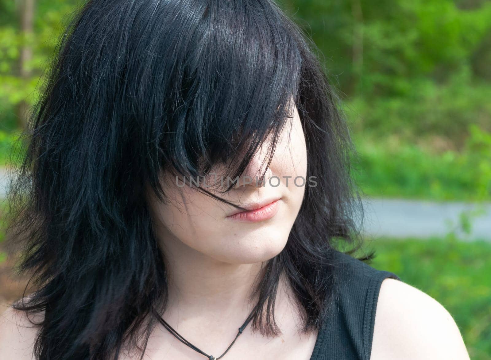 Gothic emo woman with black hair and black clothes, looking away, close-up
