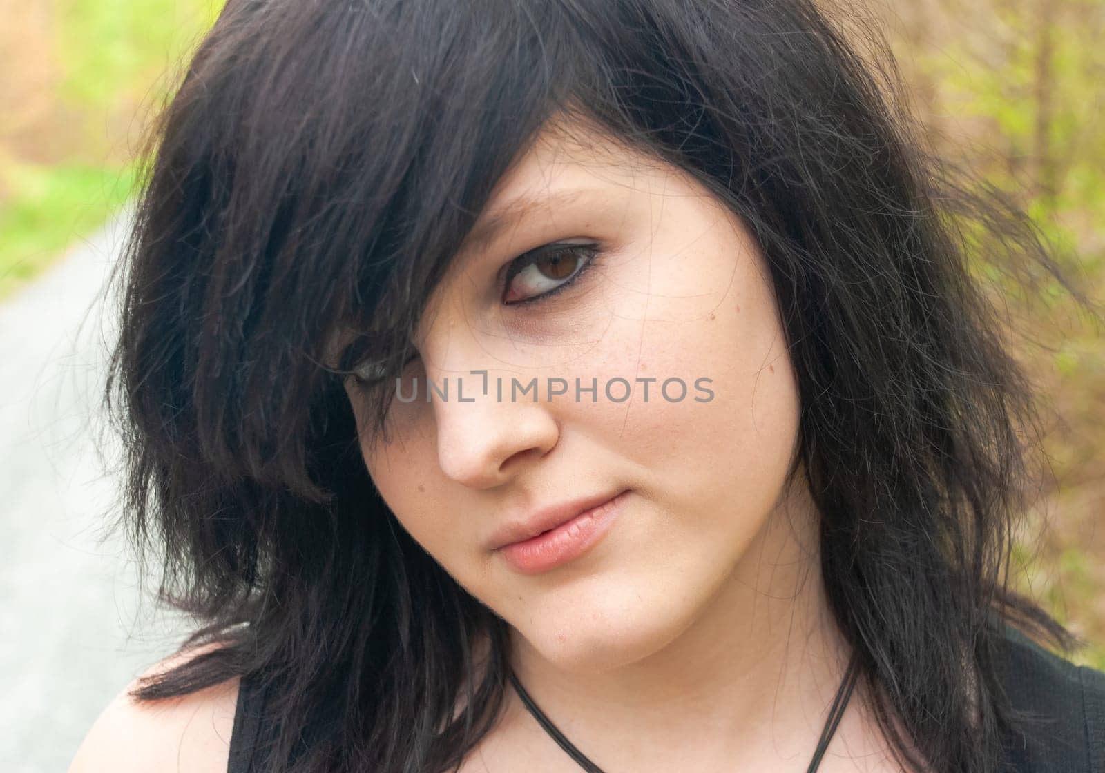 Punk emo girl, young adult with black hair and eyeliner, looking at camera, outdoors, close-up, horizontal