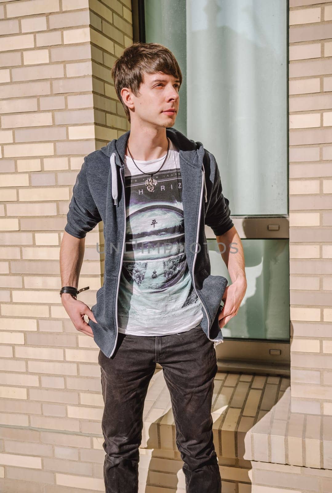 Young adult rock musician, view from the side, singer wearing a blue sweatshirt, t-shirt, standing, brown hair and beard