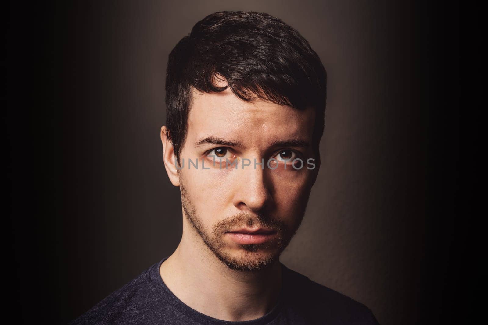 Young adult man with brown hair and beard with sceptic anger facial expression looking at camera
