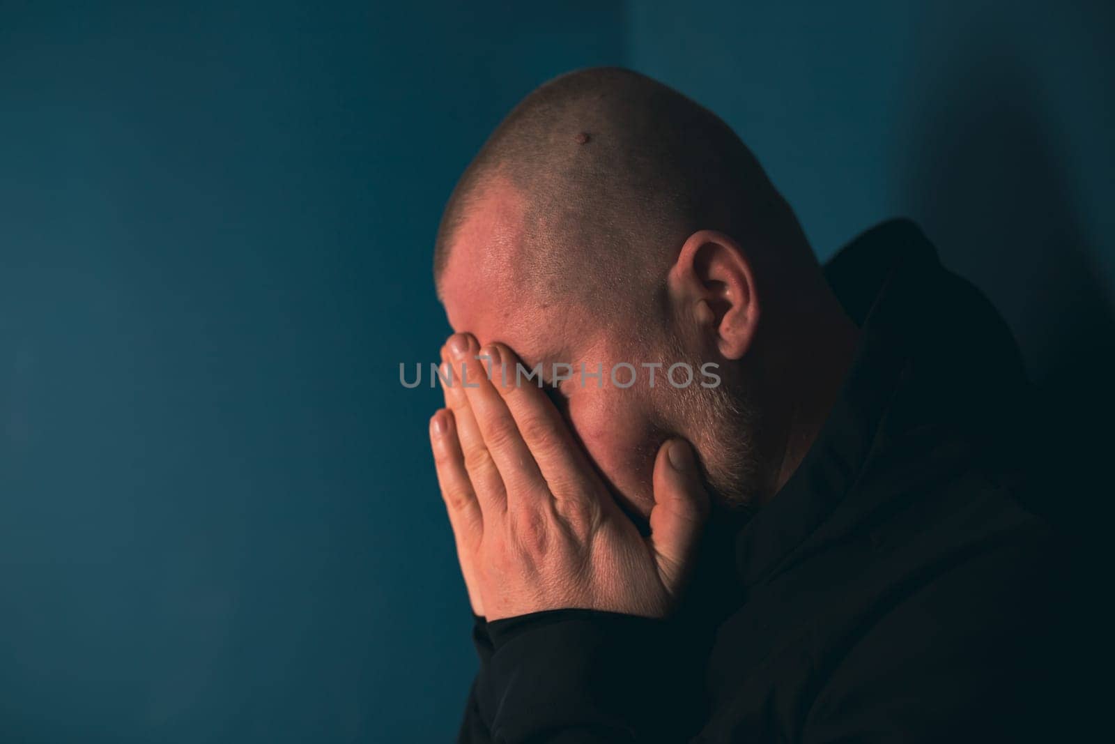 Sad man sitting in dark room. Depression and anxiety concept
