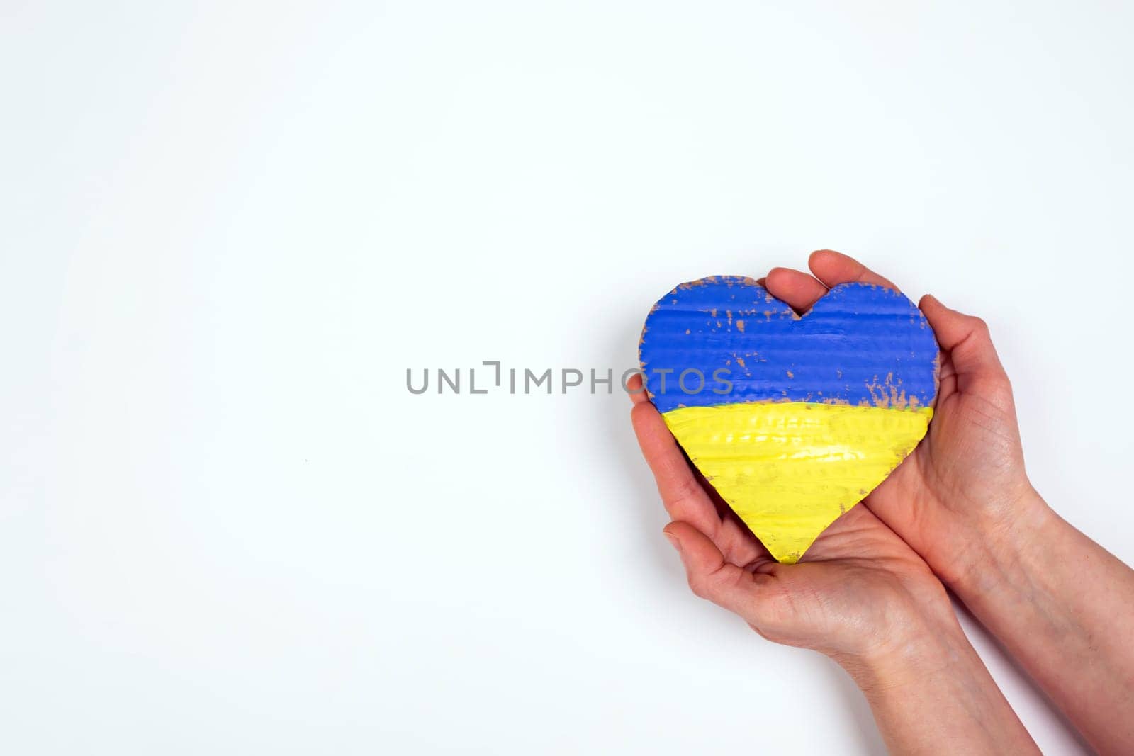 Heart shaped flag of Ukraine in female hands. The concept of solidarity with the citizens of Ukraine.