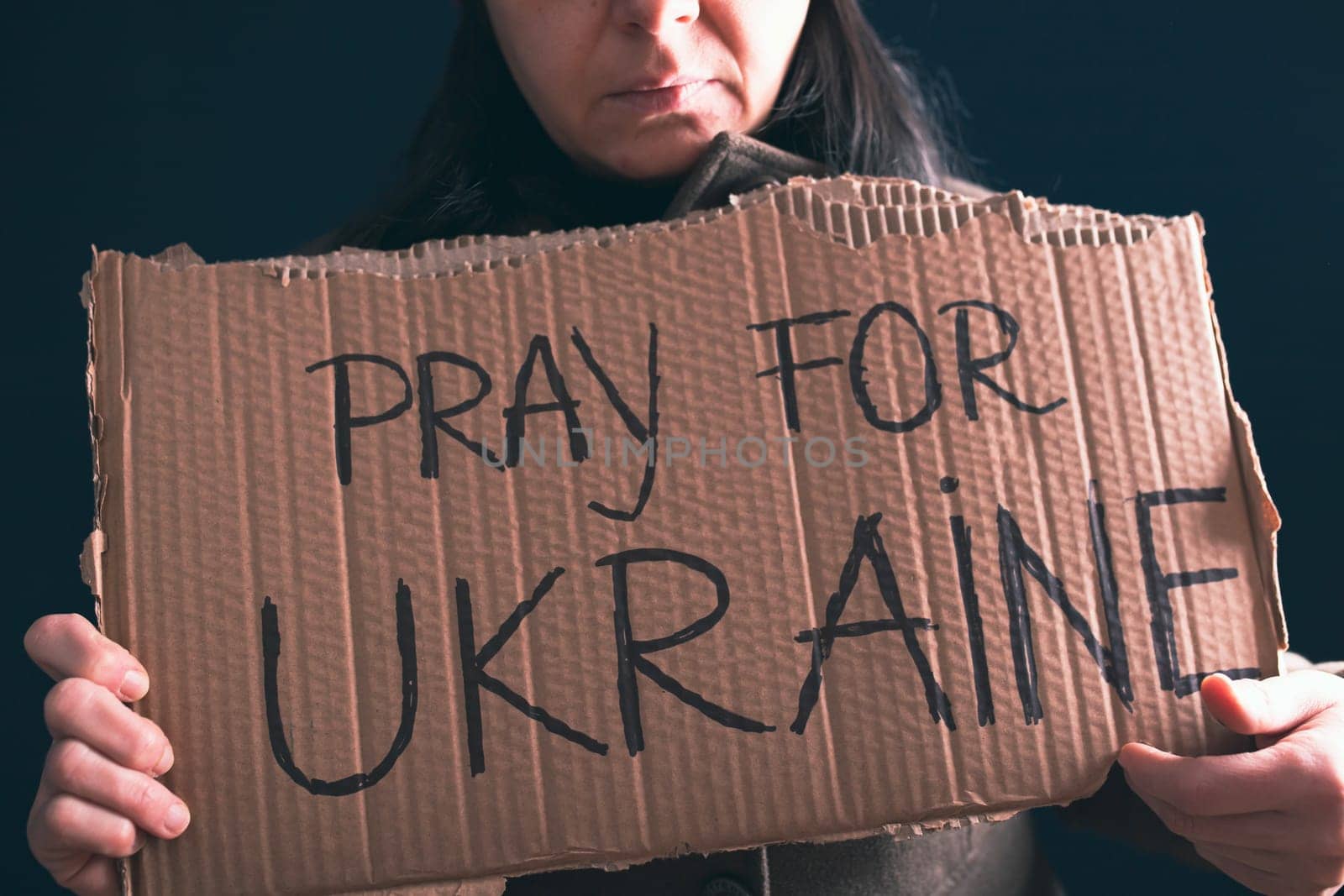 Woman holds a banner with anti-war message. Protest against the Russian intervention to Ukraine, activism and human rights movement. Concept of standing with Ukrainian.