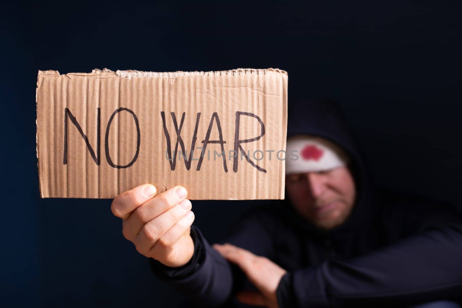 Wounded man holding placard with No war text. Stop war, russian aggression, freedom to Ukraine concept.