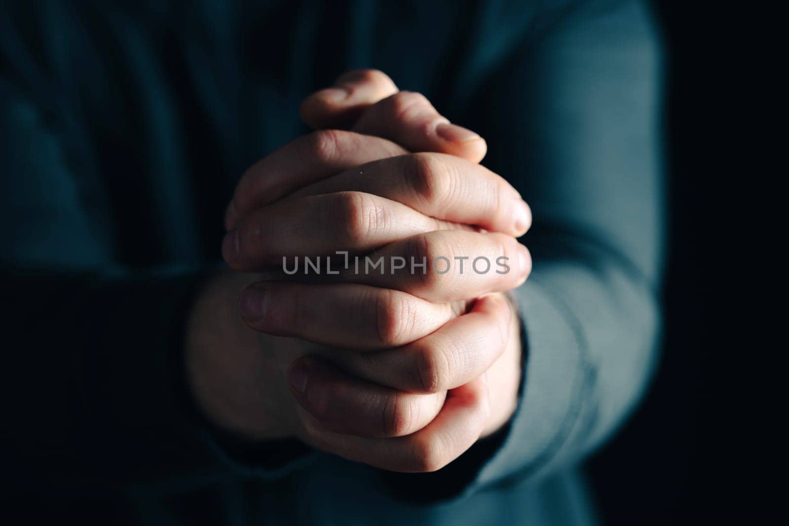 Praying hands with faith in religion and belief in God on dark background. Power of hope or love and devotion.