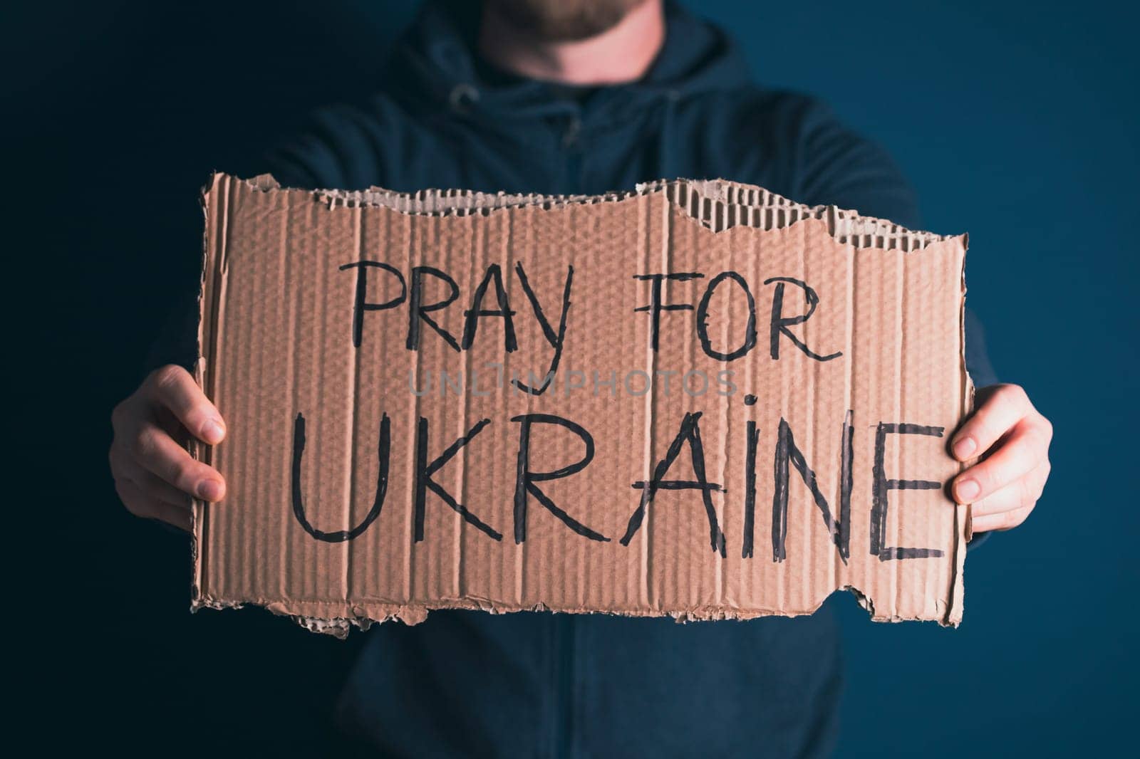 Man holding Pray for Ukraine banner. Concept symbol of help support and no war in the country of Ukraine.