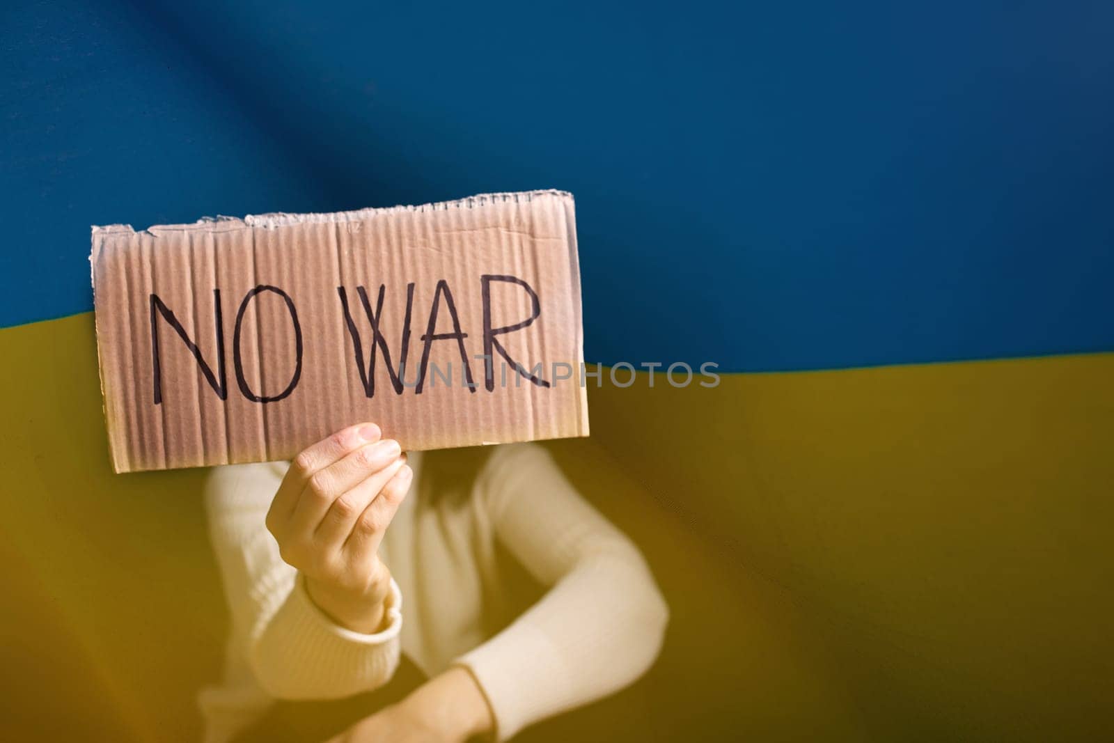 Sad woman calls to Stop war in Ukraine, raises banner with inscription No war over ukrainian flag