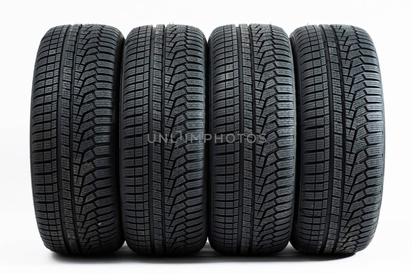 Four wheels with winter tires from front view isolated on white background. Complete set of new rubber car parts cut out on blank. Concept of safe travels.