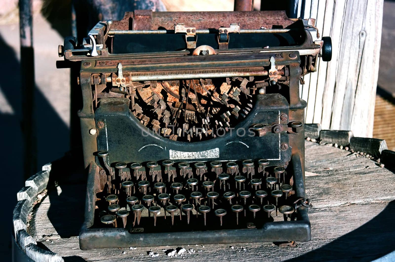 Rusted and destroyed Antique typewriter sitting on a wooden barrel
