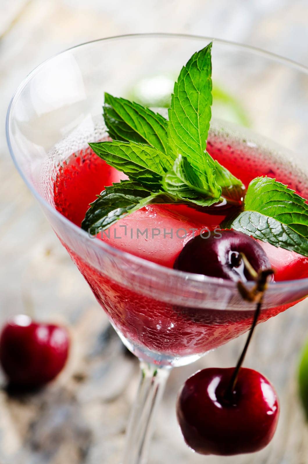 Closeup of cherry cocktail with mint on rustic table.