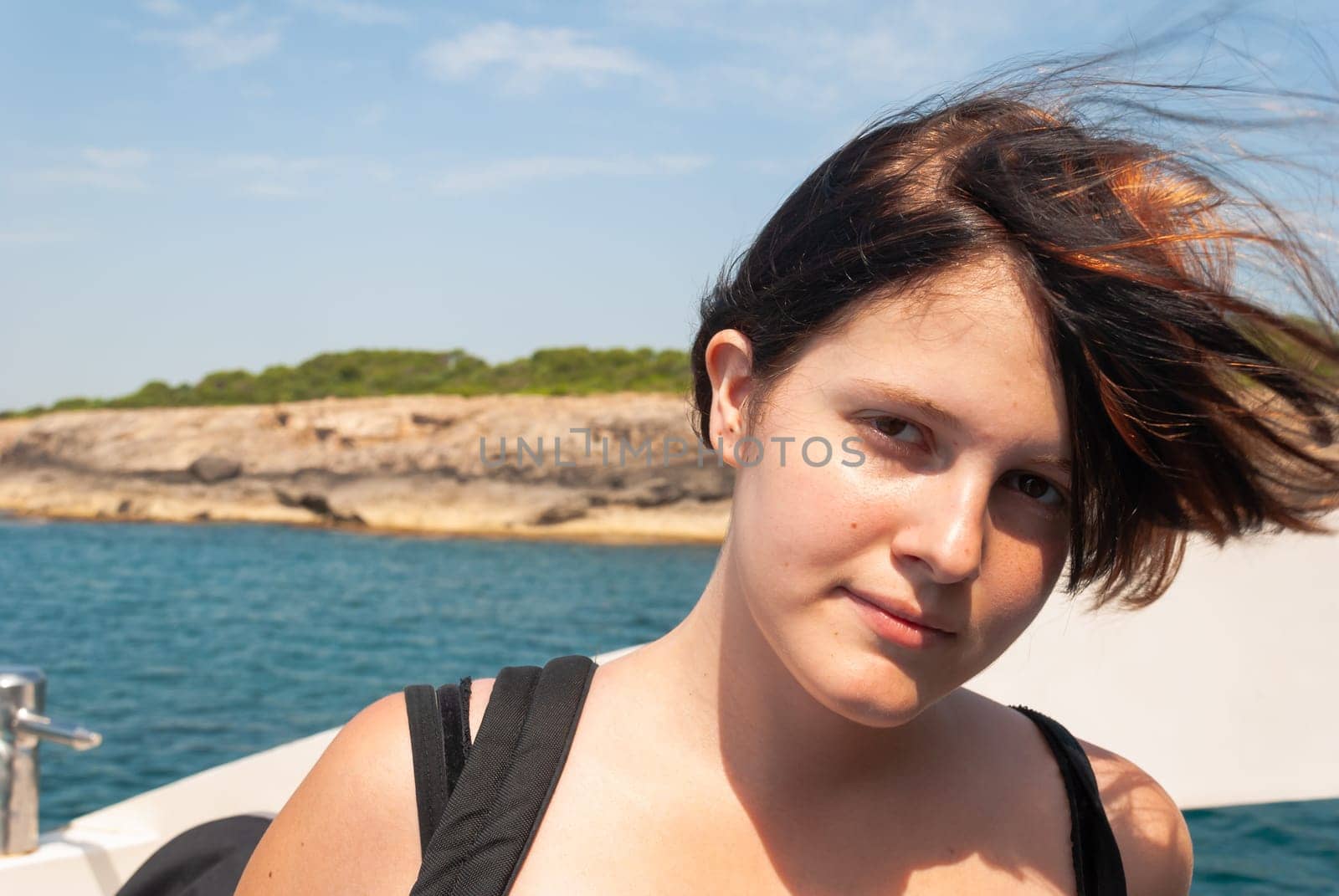 Young woman with black orange hair looking at camera while standing on a ship on the mediterranean sea, majorca