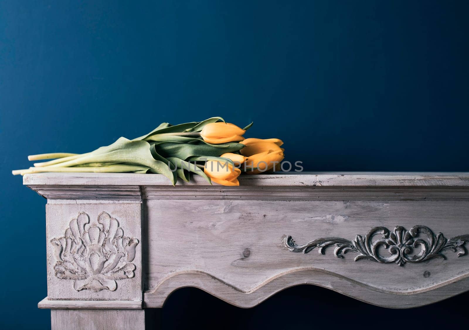 Tulip bouquet on vintage fireplace and blue wall