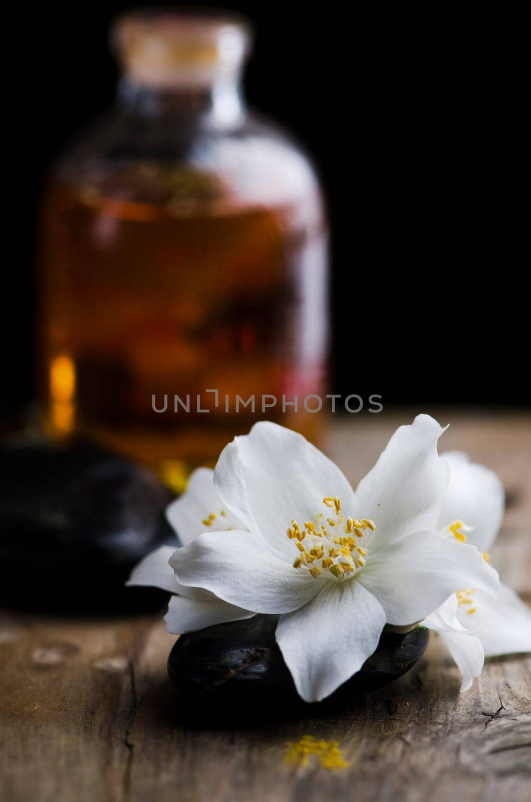 Spa concept. Jasmin flower and scented oil on wooden table.