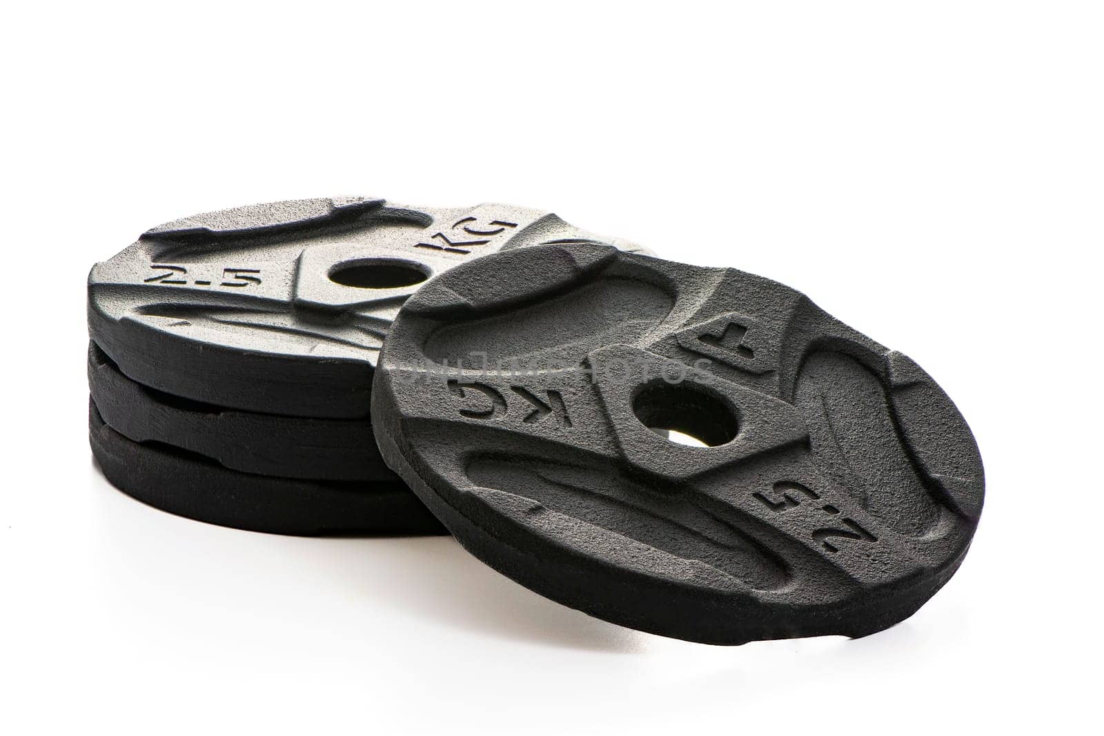 Four black metal pancakes of 2.5 kg each lie on a white isolated background. High quality photo