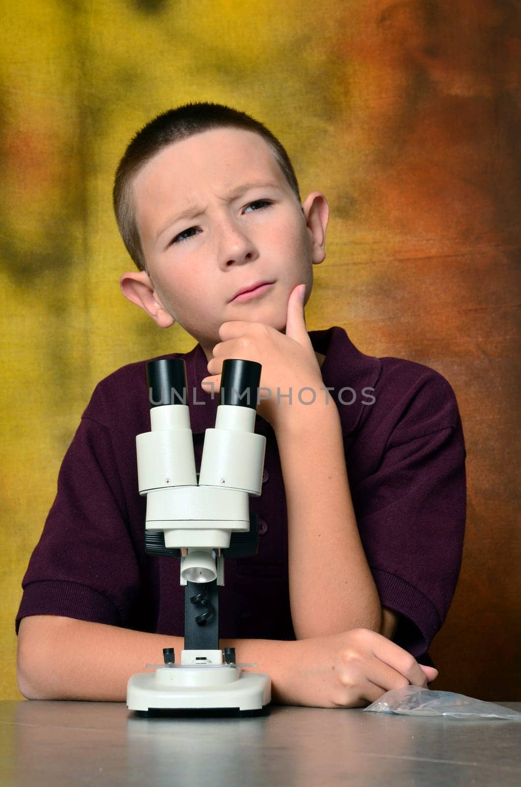 Young boy scientist with microscope examining a sample