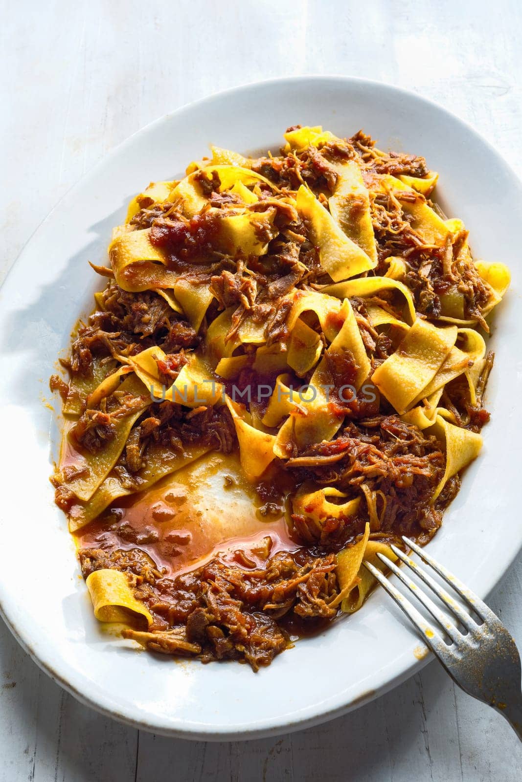 close up of plate of rustic italian pappardelle pasta in bolognese sauce