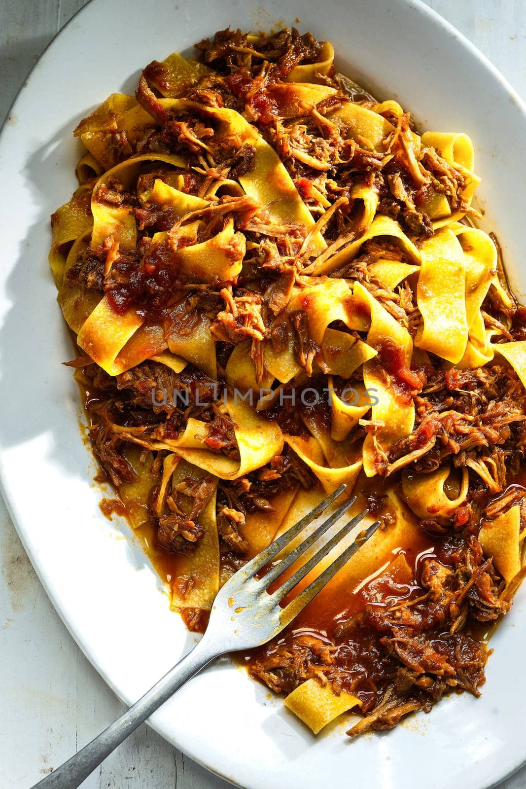 close up of plate of rustic italian pappardelle pasta in bolognese sauce