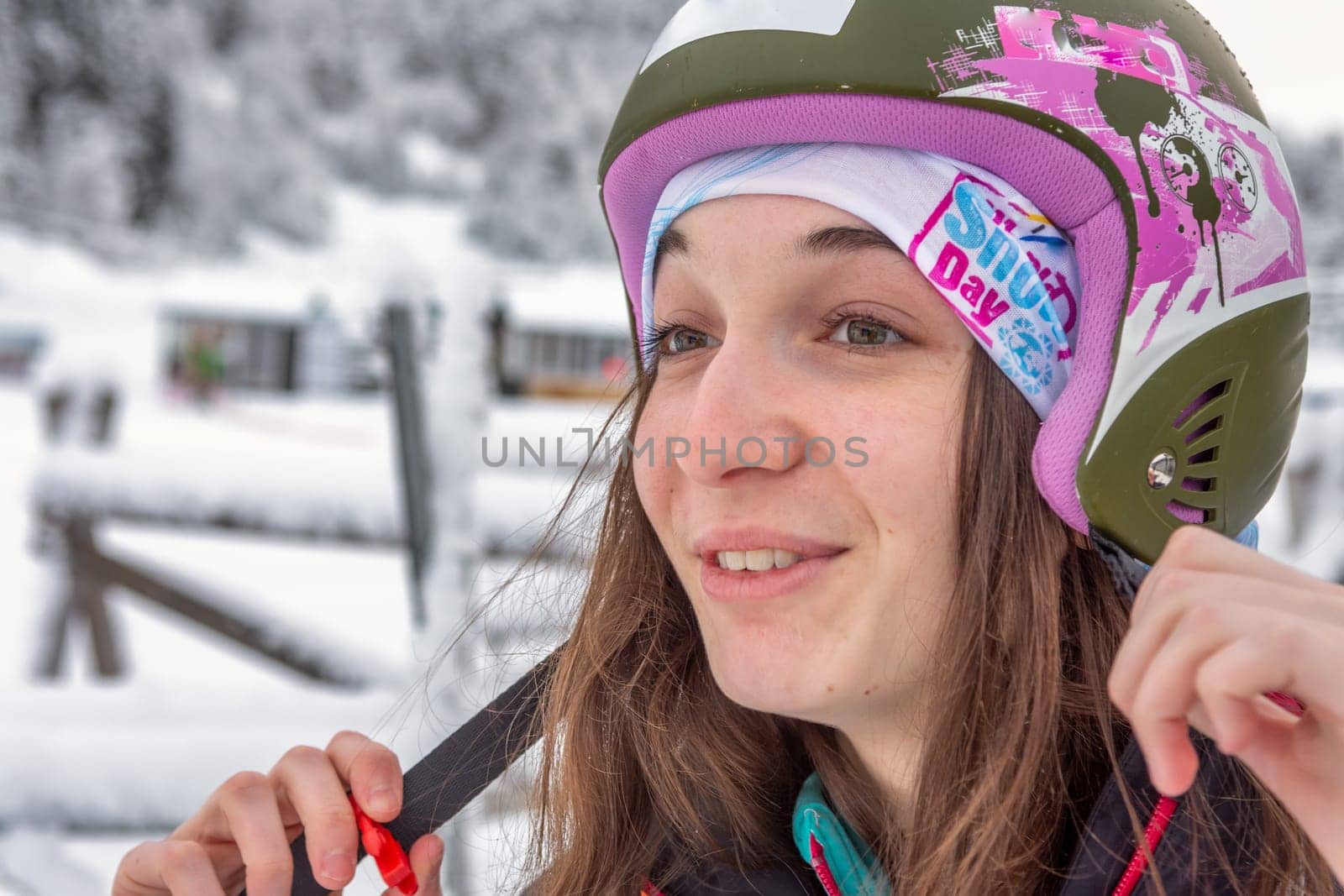 Woman with brown hair smiling while adjusting her ski helmet, getting ready for skiing in ski centre stryn, norway, close-up, horizontal