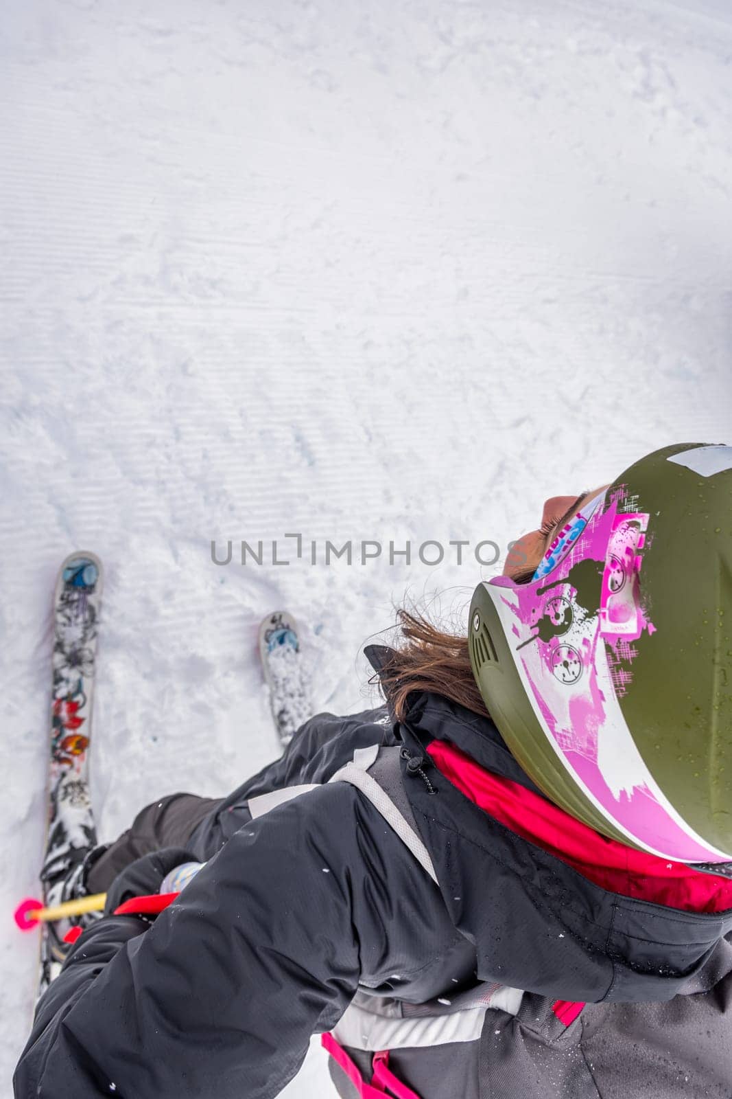 Ski Woman with brown hair wearing ski wear and helmet, standing in the valley, view from high angle, copy space, vertical