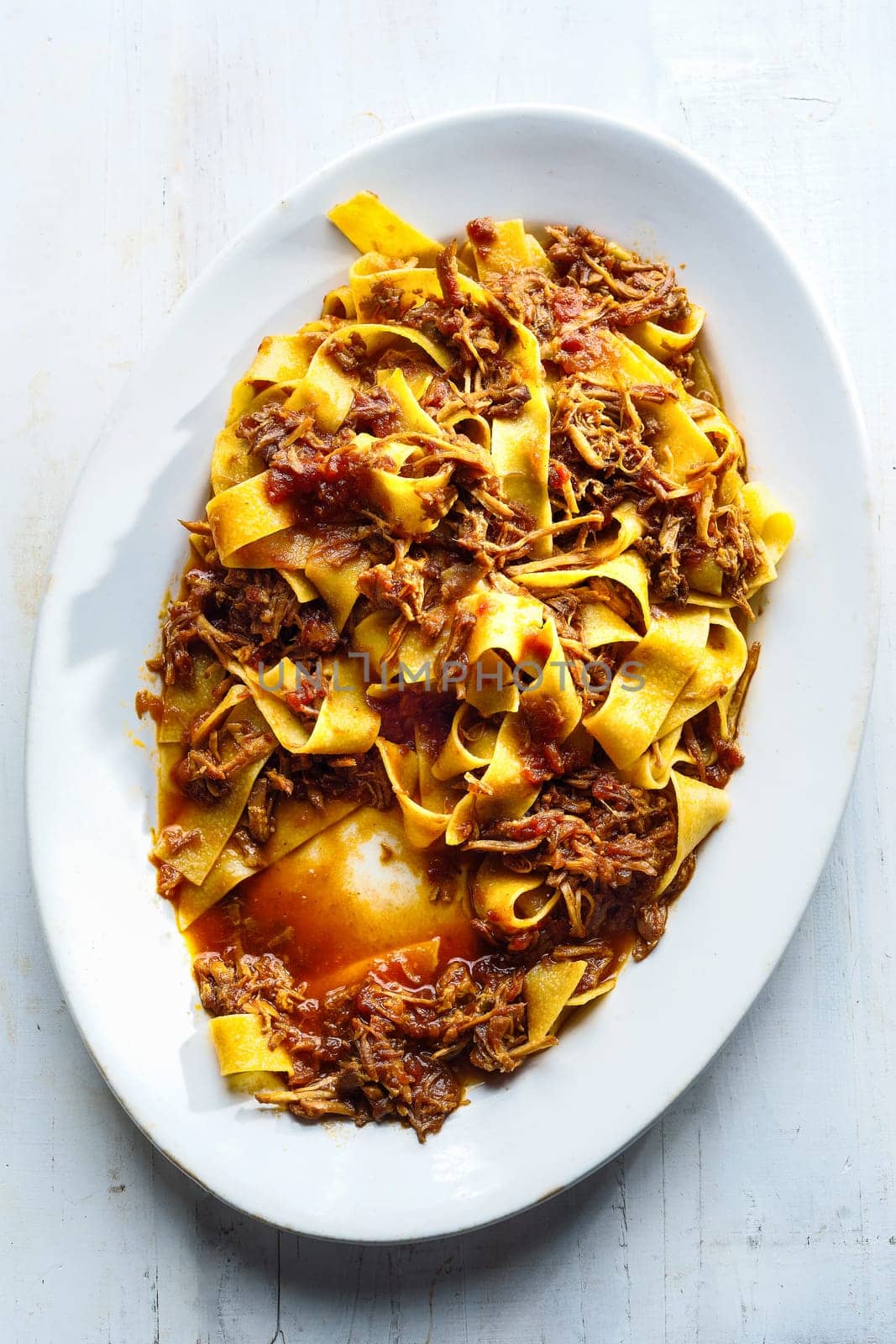 close up of plate of rustic italian pappardelle pasta in bolognese sauce
