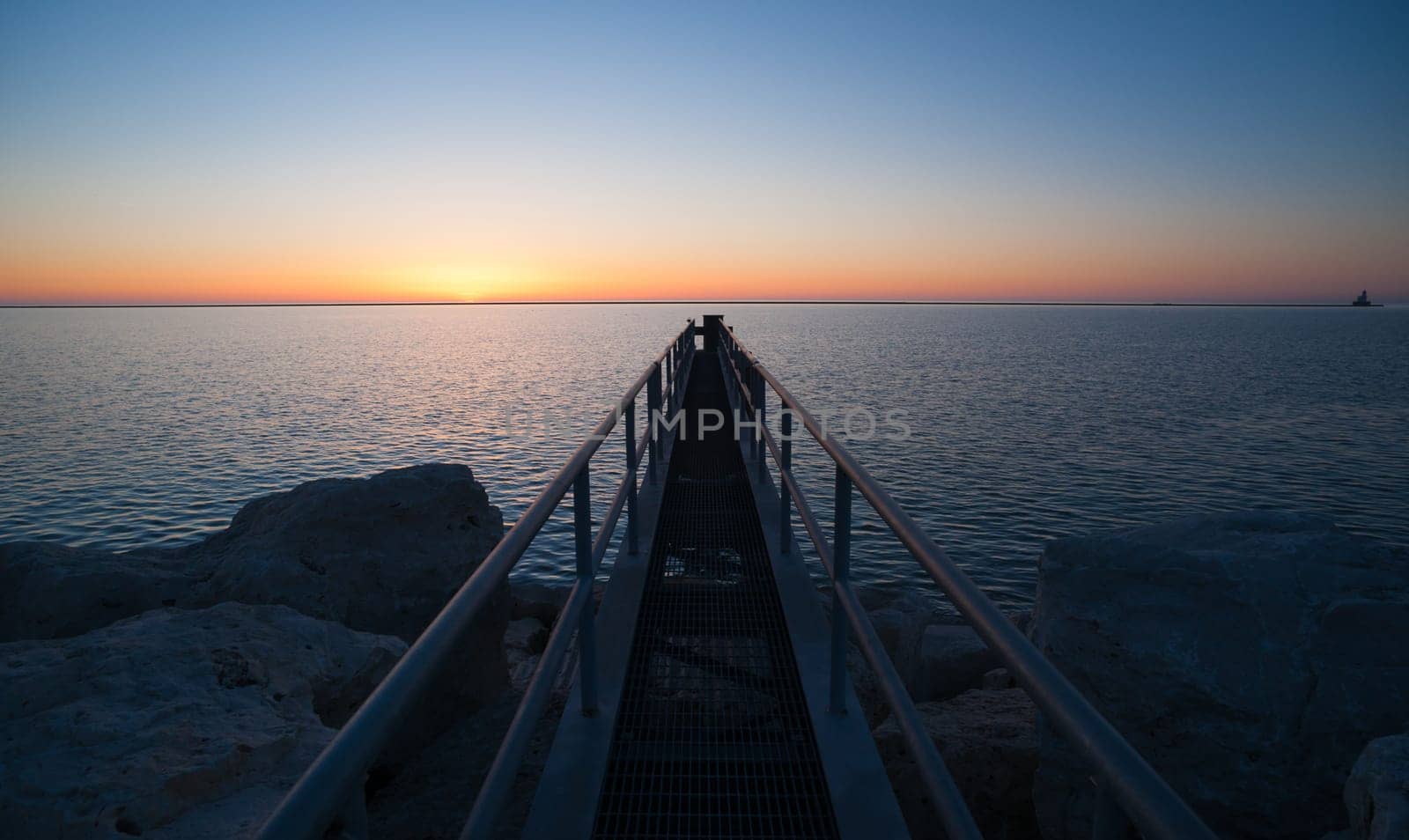 A fishing platform extendes out over Lake Michigan as the sun hits the horizon