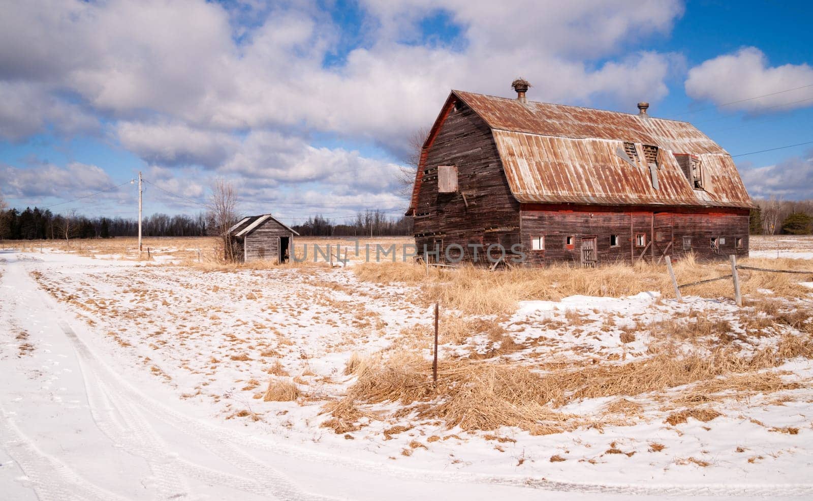 Fresh snow sits on the ground around an old barn