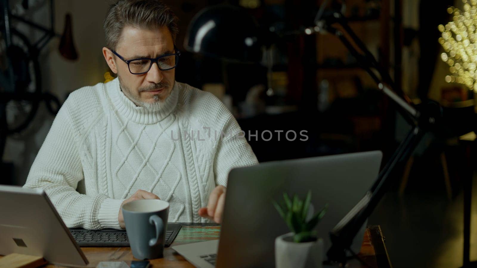 Casual man working with laptop computer in home office, happy, smiling. Mature age, middle age, mid adult man in 50s, white caucasian