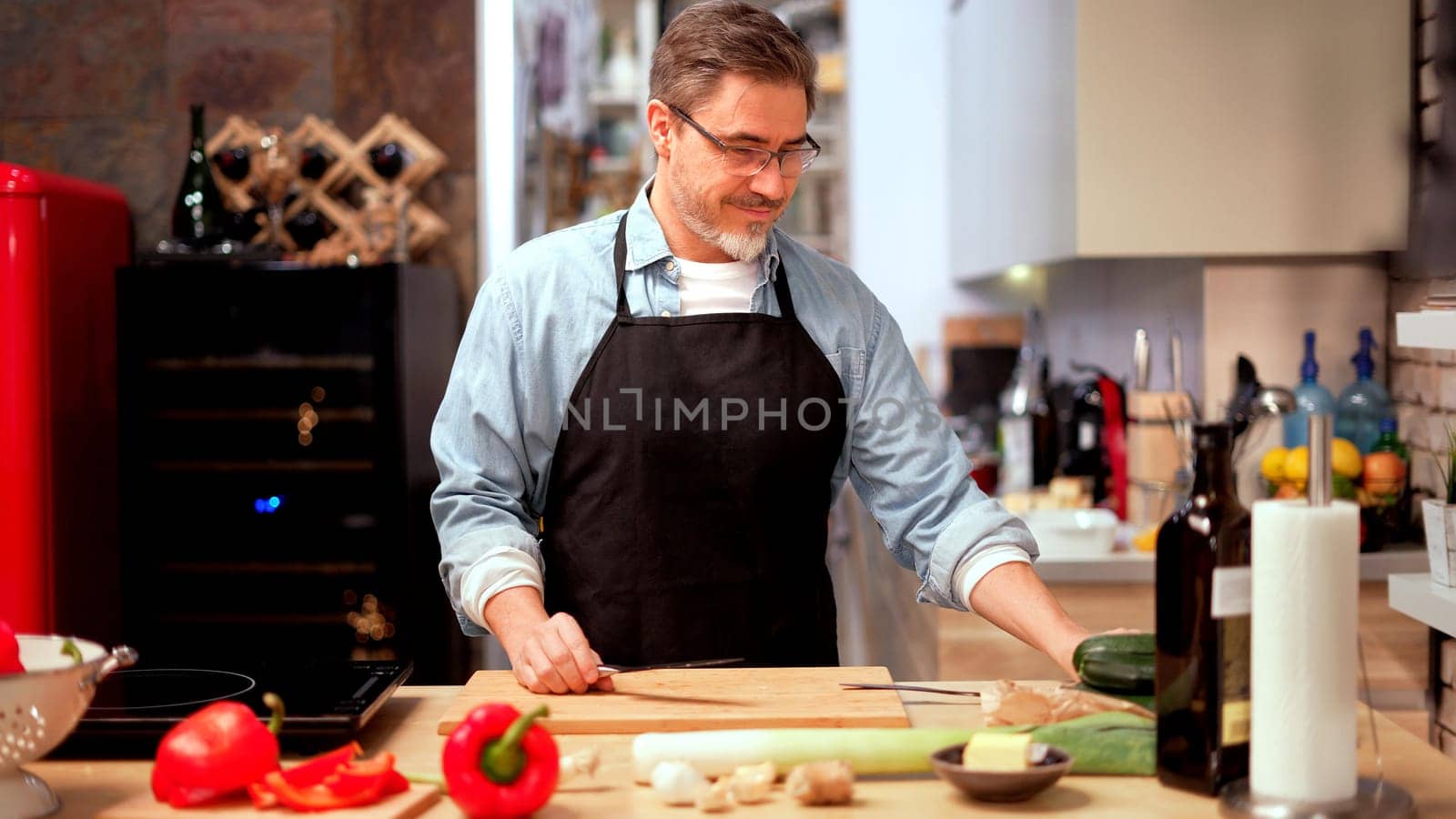 Caucasian man cooking in the kitchen at home. Mature age, middle age, mid adult white man in 50s.