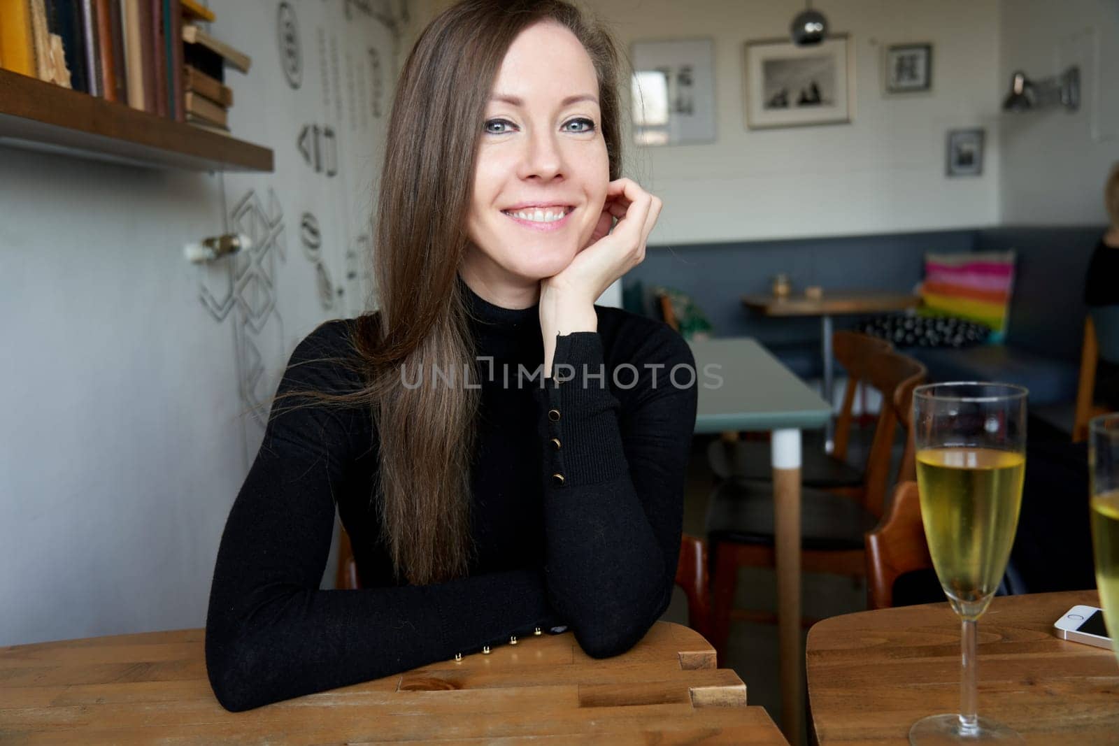 Portrait of a young white woman sitting at table smiling feeling happy in cafe.