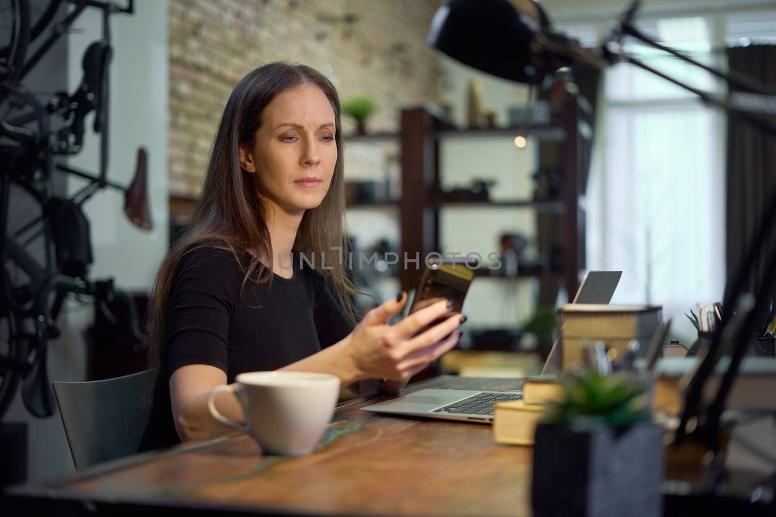 Businesswoman using laptop computer managing small business online in home office. Happy, smiling woman. Confident female entrepreneur.