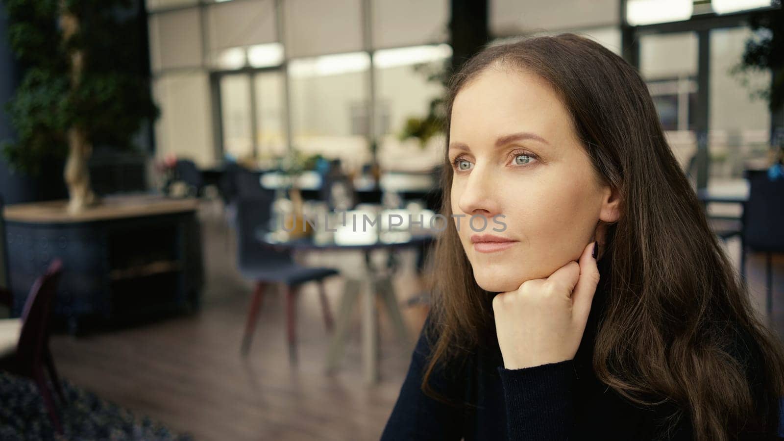 Portrait of woman sitting in restaurant, waiting, thinking, smiling.