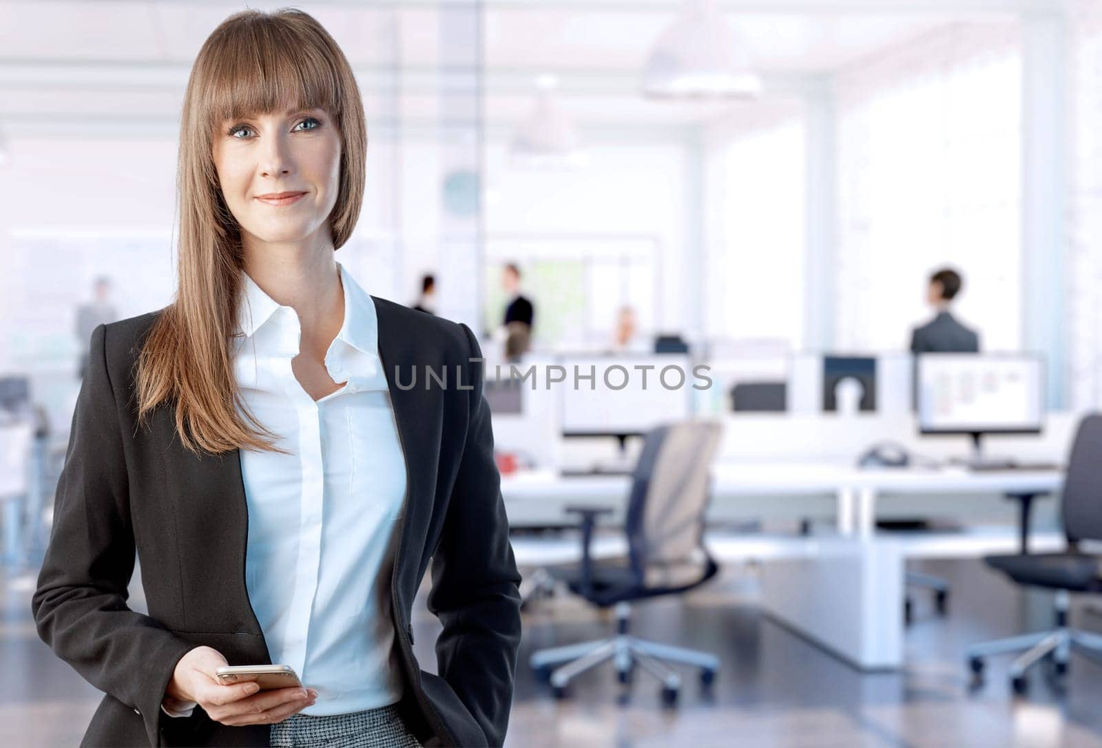 Business portrait of happy white young businesswoman with phone in office.