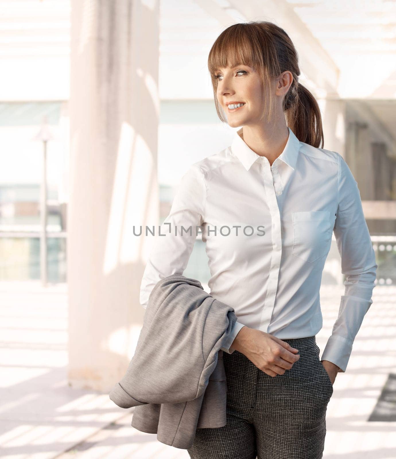 Happy young white businesswoman outdoors smiling wearing white shirt in front of business office.