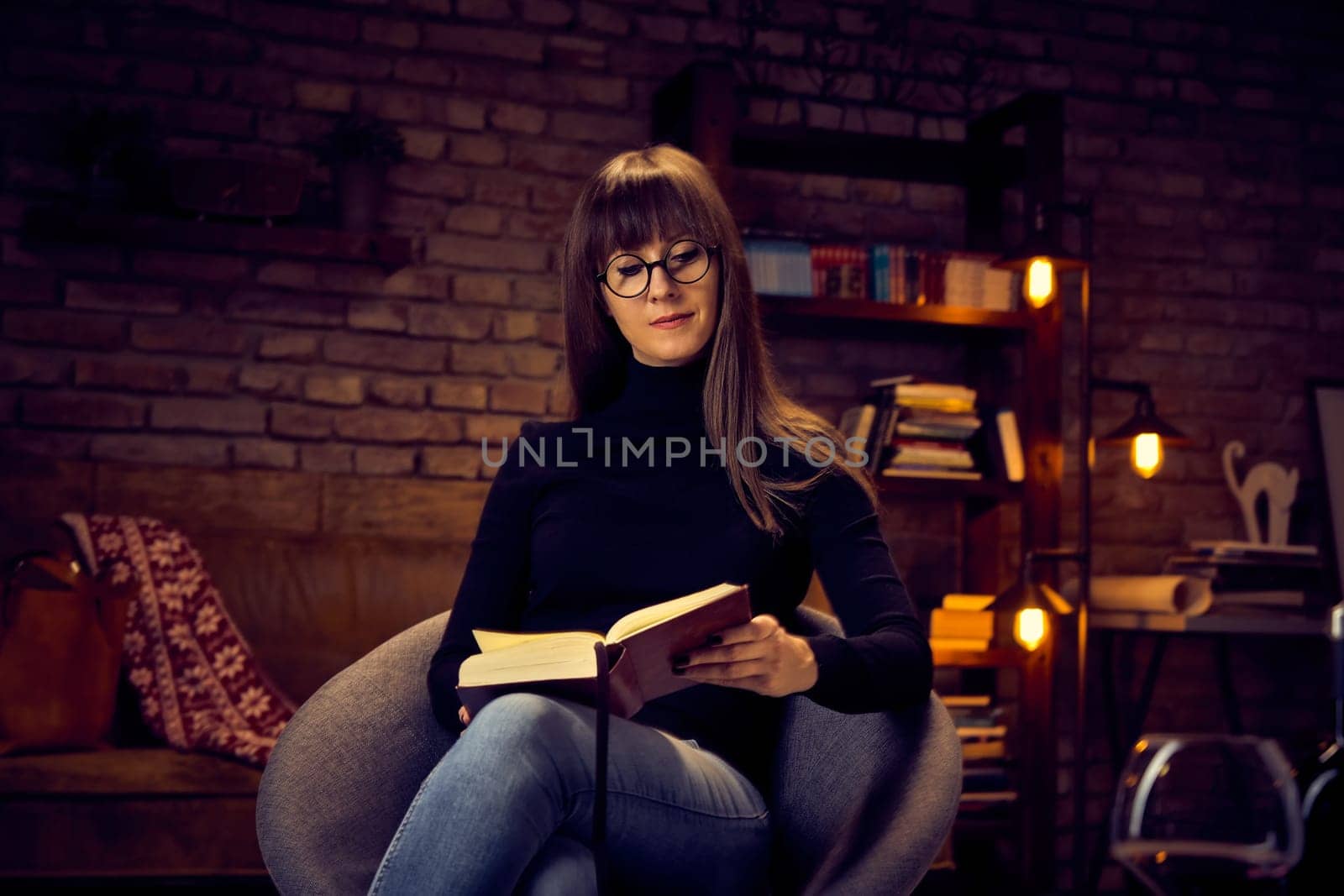 young 30s woman reading a book at home relaxing.