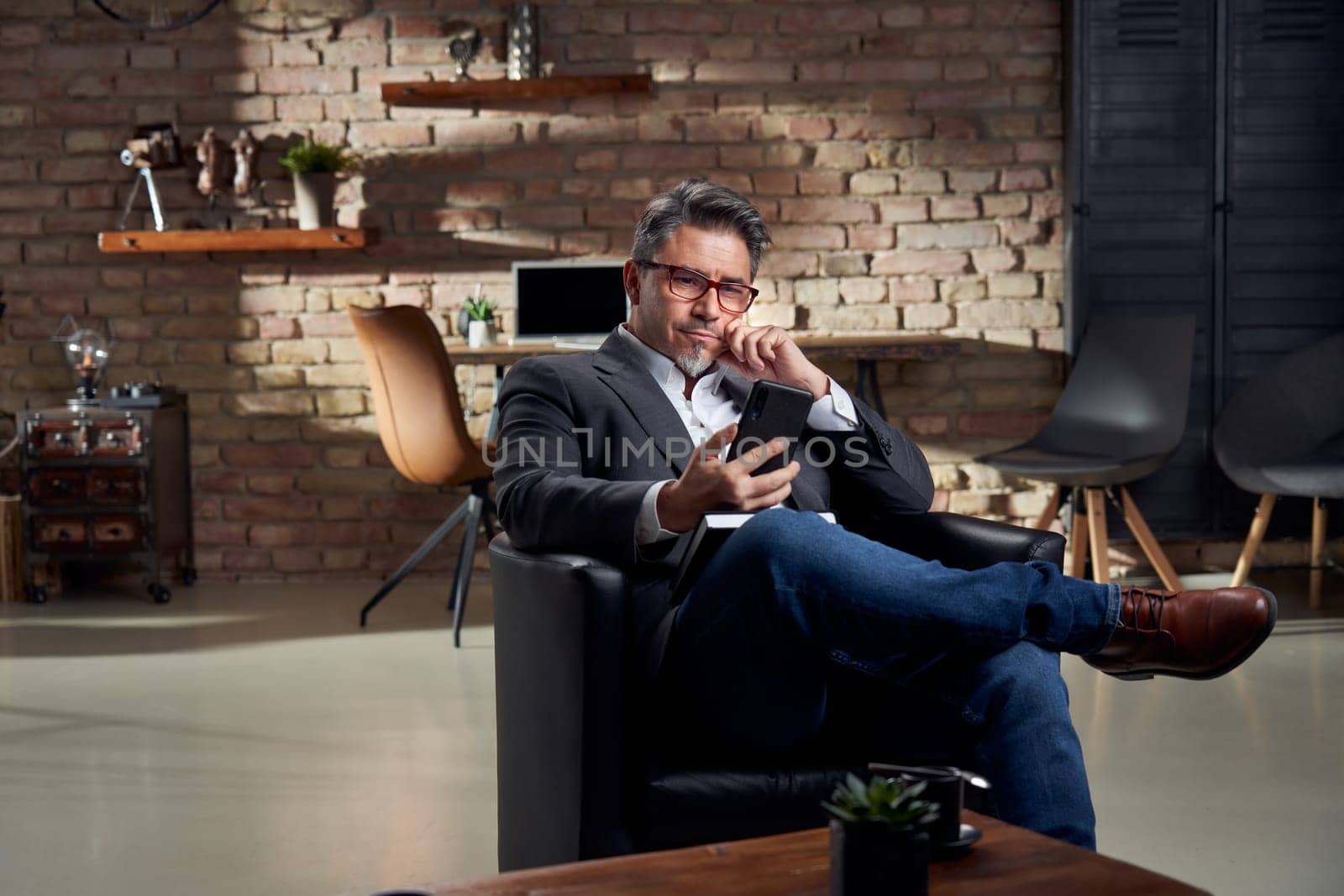 Man working in home office using phone the browse the internet.