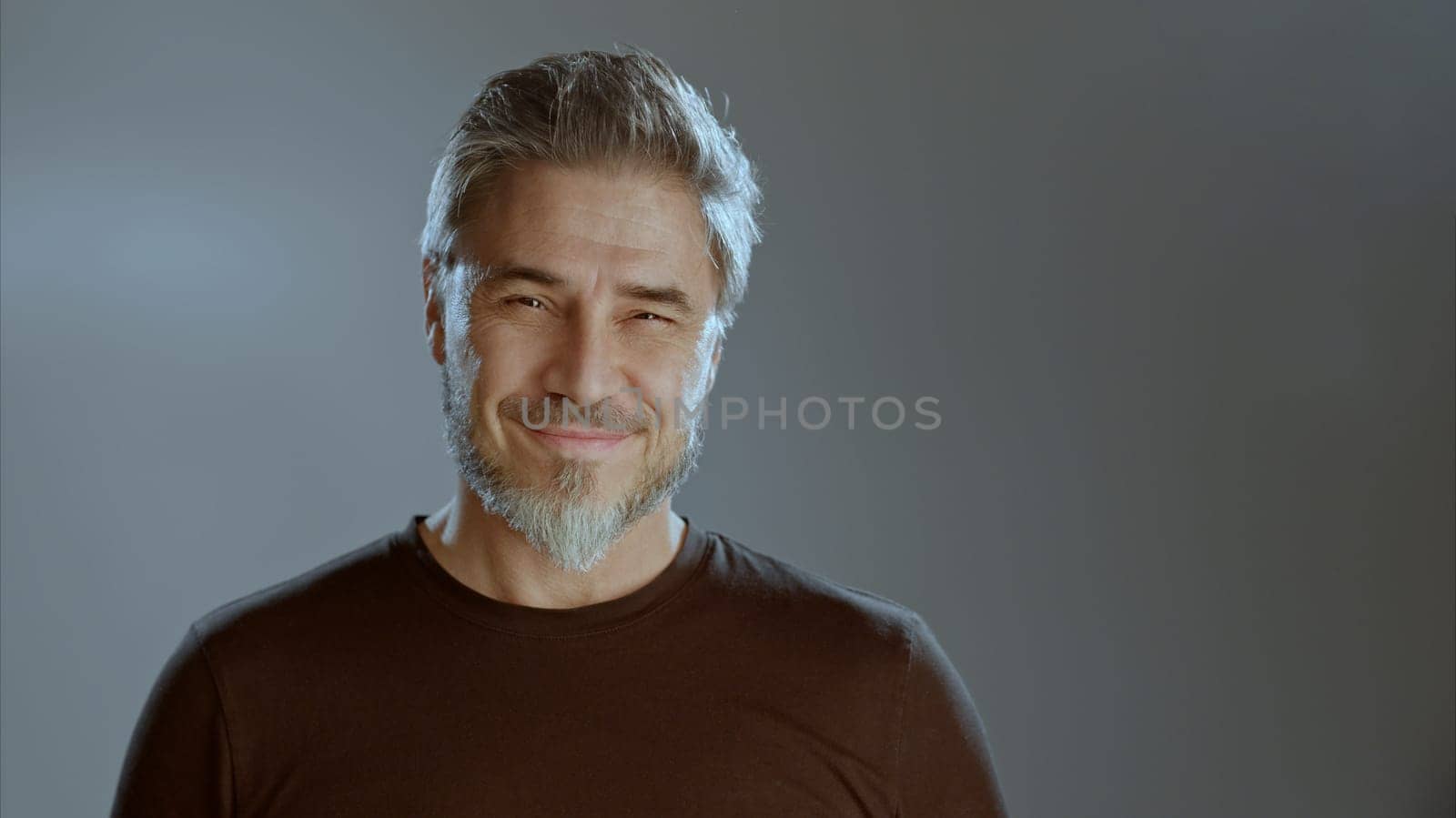 Portrait of happy older white man on gray background, smiling, copy space.