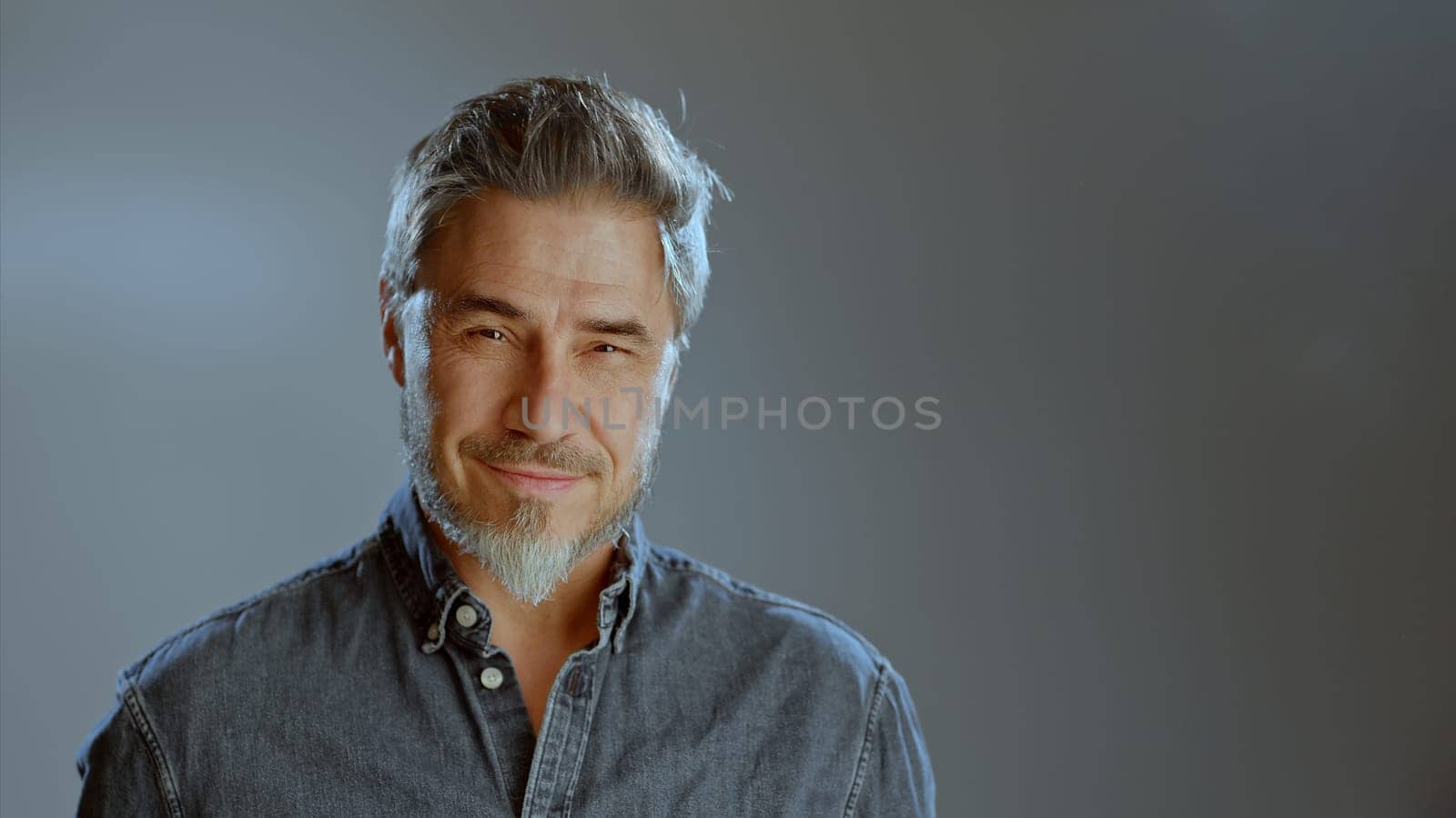 Portrait of happy older white man, beard gray hair, smiling. Copy space for text gray background