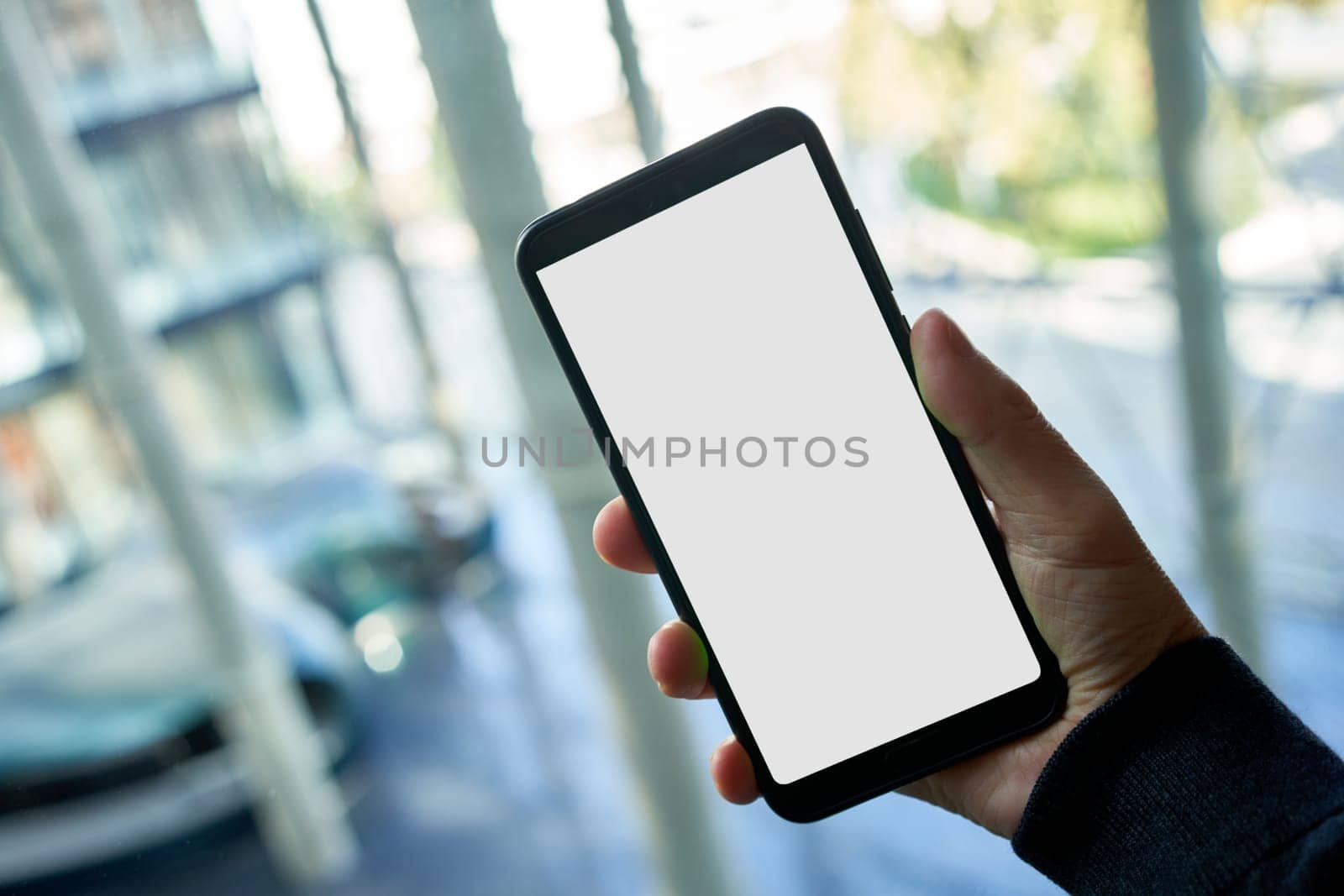 Hand holding mobile phone with blank screen in modern office, walking, moving.
