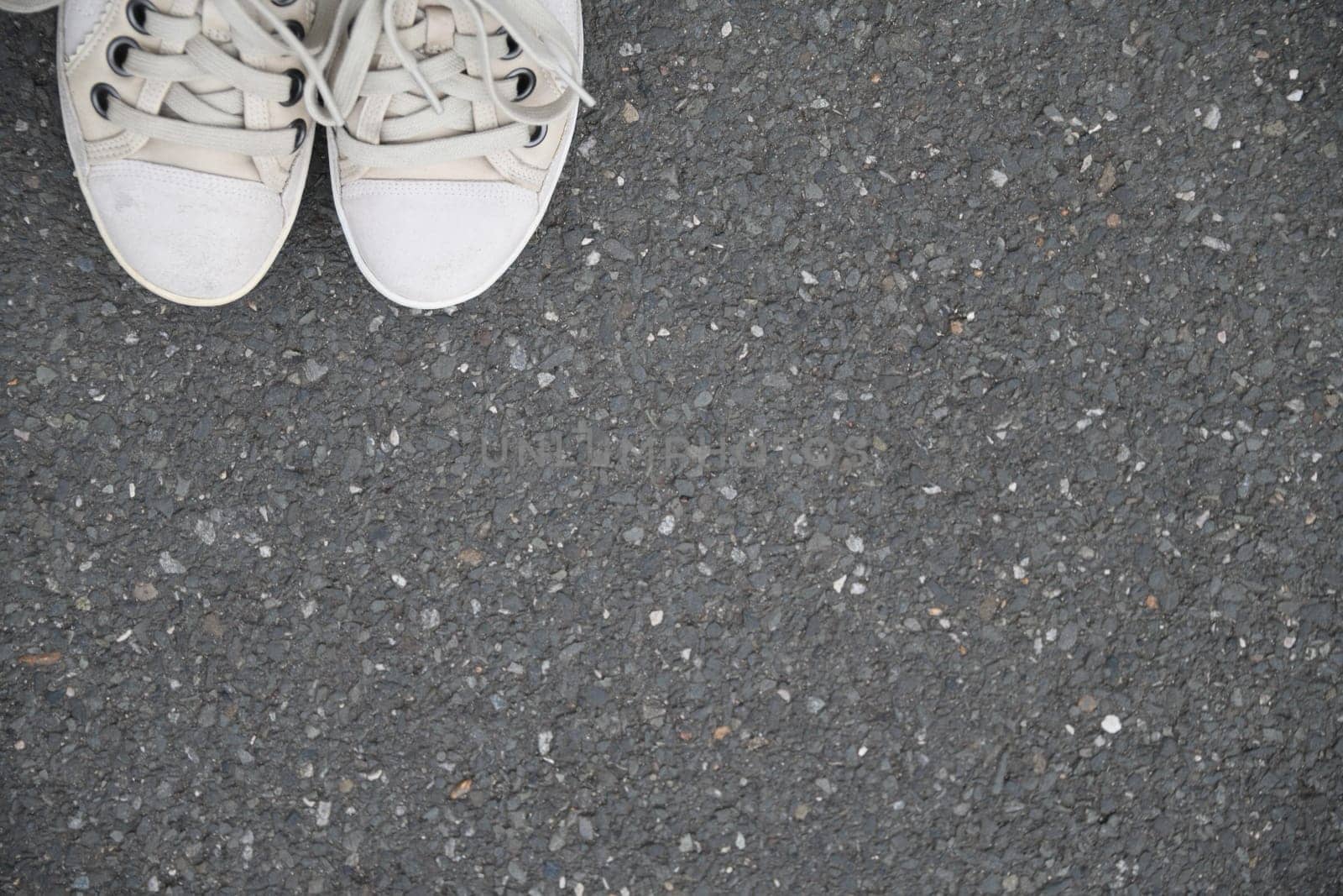 Go new ways. White shoes on the asphalt of a gray street.