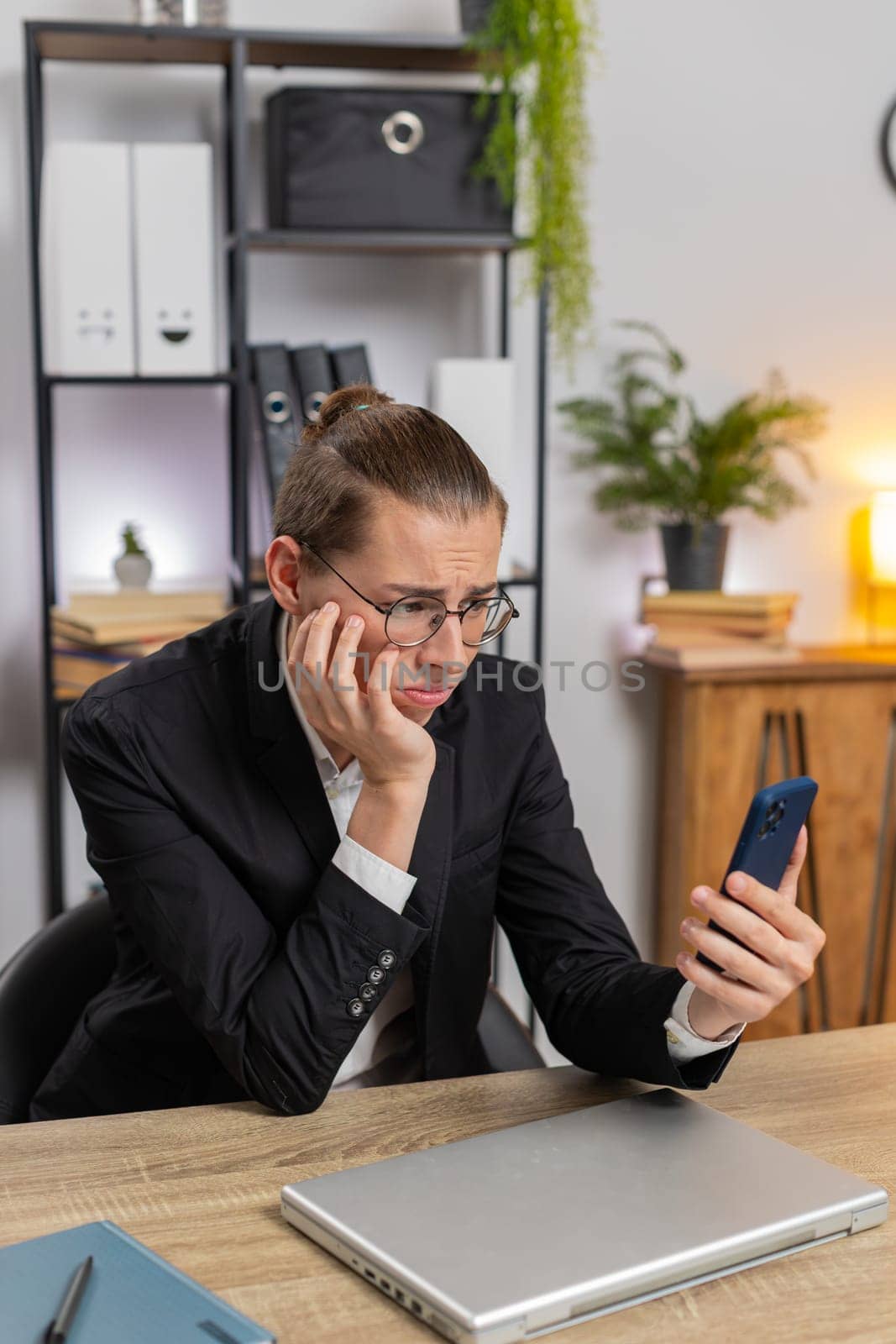 Caucasian young stylish man using smartphone typing browsing, loses becoming surprised sudden lottery results, bad news, fortune loss fail at home office desk workplace. Upset freelancer guy worker.