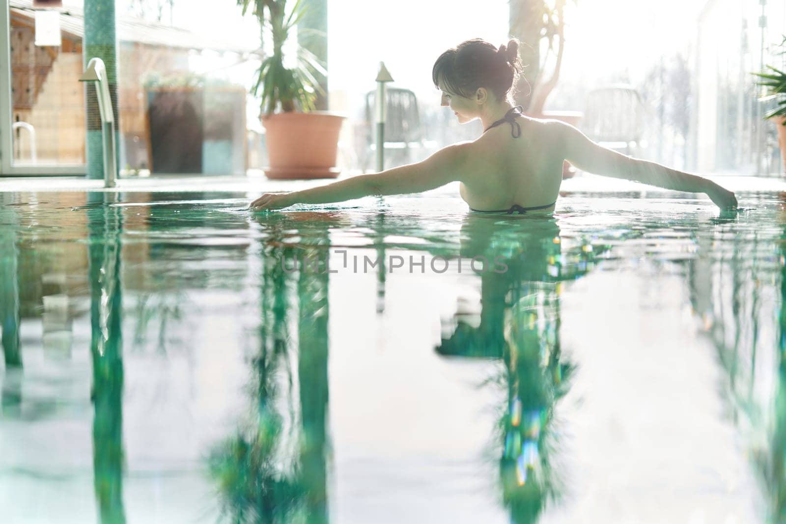 Wellness - white woman in her 30s enjoying water in pool, smiling.
