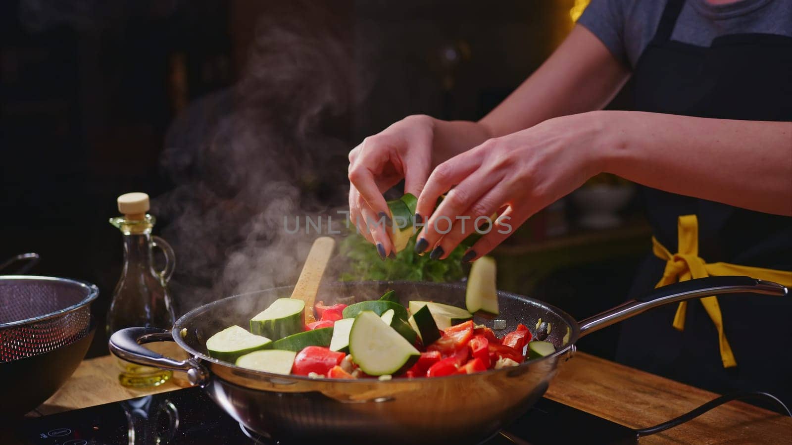 Woman cooking frying in wok pan on kitchen table.