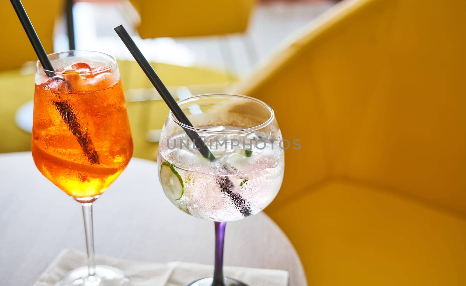 Glass of cold refreshing aperol spritz and gin tonic cocktail on table in summer.