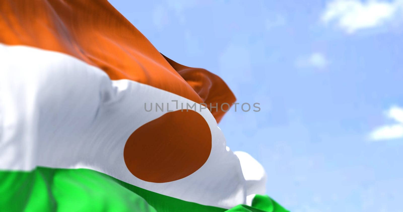 Detail of the national flag of Niger waving in the wind on a clear day. Niger is a landlocked country in West Africa. Selective focus.